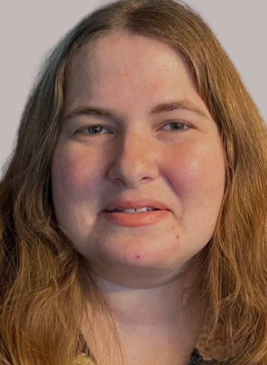 A woman with long, light brown hair smiles softly at the camera, embodying the welcoming spirit of our About Us page. She has fair skin and is photographed against a plain, light background.